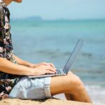 Homme assis à la plage avec son ordinateur portable