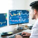 Homme devant trois ecrans trading