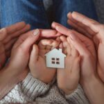 Une maison miniature dans les mains d’une famille