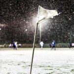 drapeau et joueurs de foot sous la neige en fond