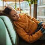 femme portant une tasse couchée sur un canapé