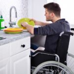 Un homme en fauteuil roulant fait la vaisselle