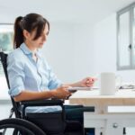 Femme en fauteuil roulant travaille sur son bureau