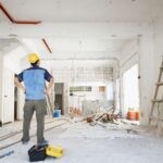 homme qui regarde l’intérieur d’une maison en rénovation