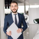 Smiling Car Salesman in Showroom