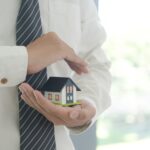 personne qui tient une maquette de maison