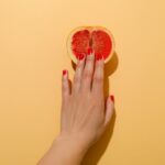 Female hand and grapefruit on beige background