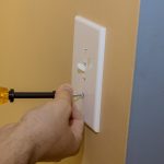 Removing white light switch cover plastic on preparation wall for new paint wall