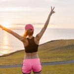 Young woman looking at the sea after workout with arms out